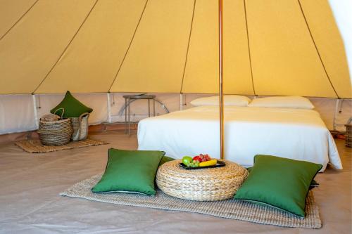 a tent with a bed and a basket of fruit at Pura Eco Retreat, Jebel Hafit Desert Park in Al Ain