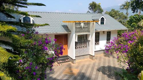een klein huis met paarse bloemen ervoor bij Blanc Villa in Munnar