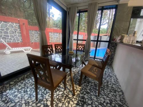 a dining room with a glass table and two chairs at West Valley Villa , Casa Raywood in Lonavala
