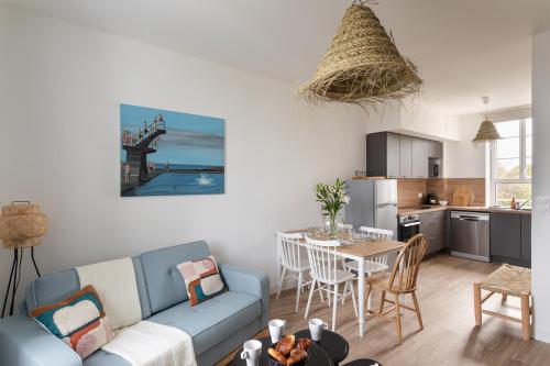 un salon avec un canapé bleu et une cuisine dans l'établissement Le Coup de Soleil - Proche Plage de Rochebonne, à Saint-Malo