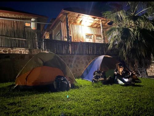 two tents in the grass in front of a house at Kivu Macheo eco-lodge in Kibuye