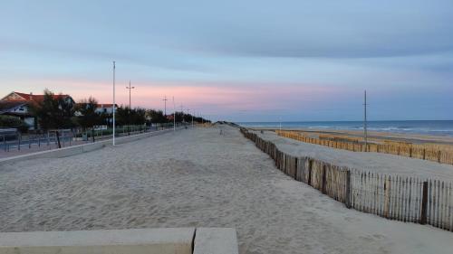 a sandy beach with a fence and the ocean at Hôtel Michelet Plage in Soulac-sur-Mer