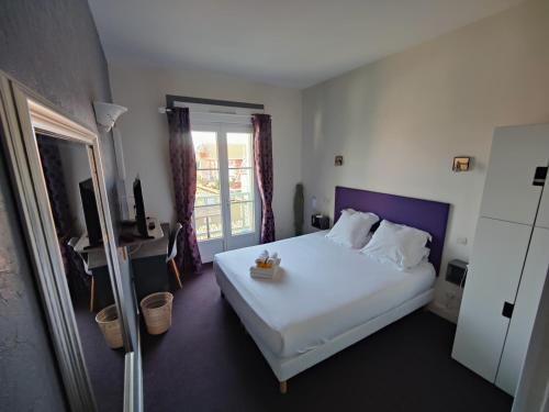 a bedroom with a white bed and a balcony at Hôtel Michelet Plage in Soulac-sur-Mer