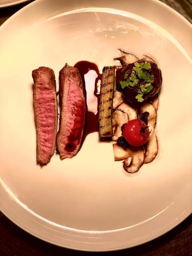 a white plate with two pieces of meat and vegetables at Grand Hôtel Mölle in Mölle
