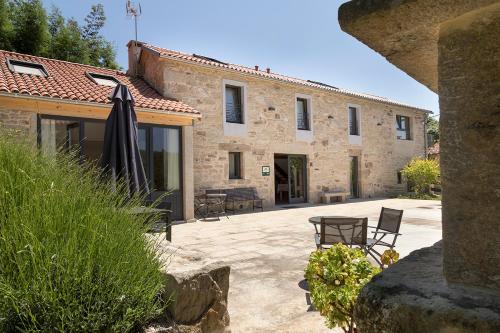 a large stone building with a patio and an umbrella at Landras de Compostela in Santiago de Compostela