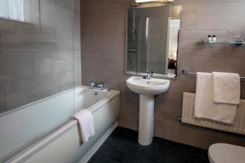 a bathroom with a sink and a toilet and a bath tub at Weston Hall Hotel Sure Hotel Collection by Best Western in Bulkington