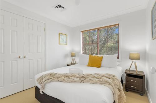 a white bedroom with a large bed and a window at Orion Beach Retreat in Vincentia