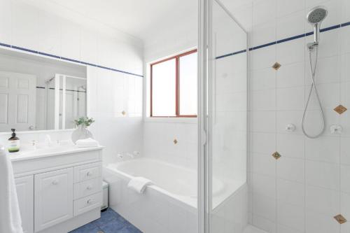 a white bathroom with a shower and a tub and a sink at Orion Beach Retreat in Vincentia