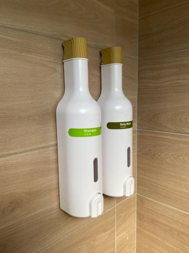two white bottles sitting on top of a wooden floor at Warmday Homestel in Chiayi City