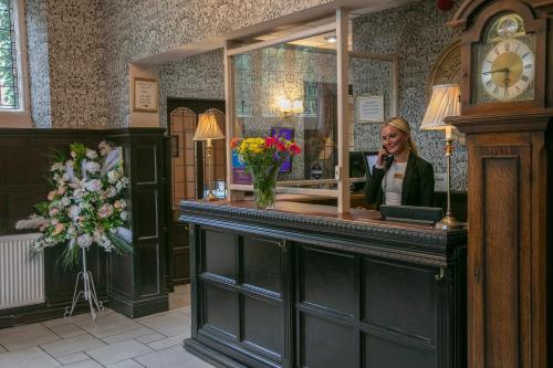 a woman is standing behind a counter in a salon at Weston Hall Hotel Sure Hotel Collection by Best Western in Bulkington