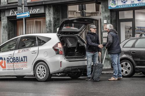 two men standing next to a white car with its door open at SUITE ANGOLO ALLA STAZIONE - Appartamento con terrazzo panoramico in Pavia