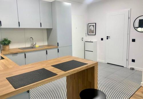 a kitchen with white cabinets and a wooden counter top at Platon Residence Apartments in Łódź