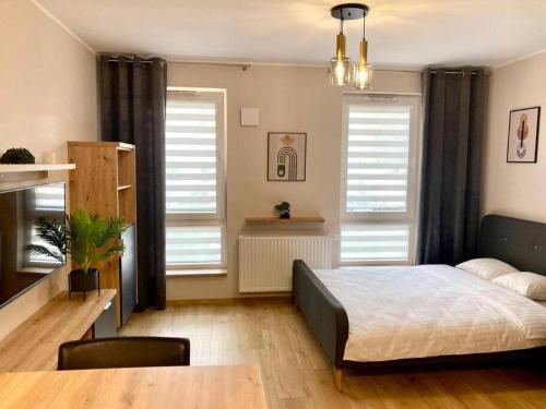 um quarto com uma cama, uma mesa e janelas em Platon Residence Apartments em Lódź