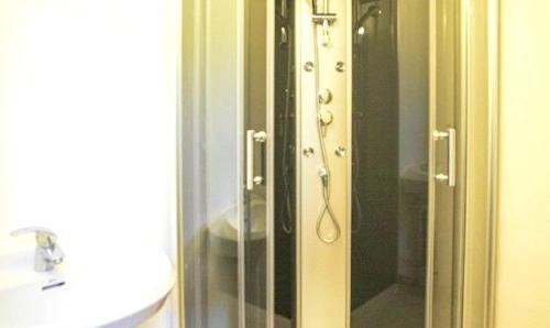 une salle de bain avec une douche en verre avec un lavabo dans l'établissement Ancienne maison de ferme avec vue montagne à Cheylade, à Cheylade