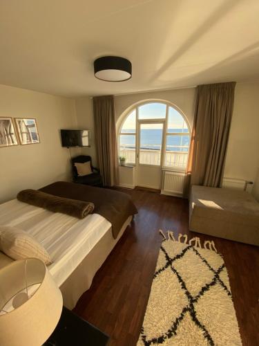 ein Schlafzimmer mit einem Bett und einem großen Fenster in der Unterkunft Grand Hôtel Mölle in Mölle