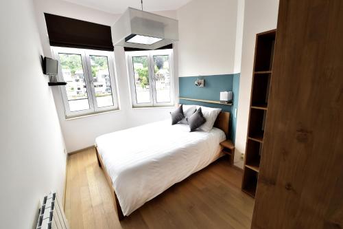 a bedroom with a white bed and two windows at Côté Sax bed and breakfast in Dinant