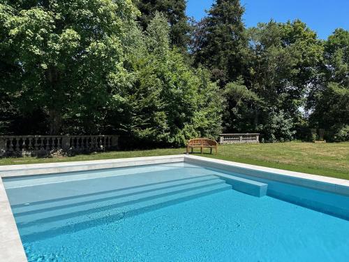 a blue swimming pool with a bench in a yard at Villa Moncoeur in Remiremont