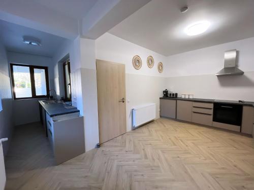 een keuken met witte muren en een houten vloer bij Casa Forrest & SPA in Muntele Săcelului