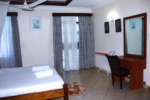 a bedroom with a bed and a desk and a mirror at Gifts Aden apartments in Mombasa