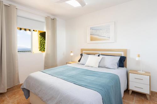 a white bedroom with a bed and a window at Playa La Arena with pool and privat parking in Puerto de Santiago