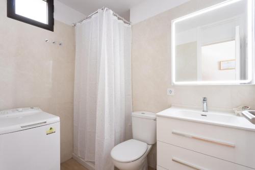 a white bathroom with a toilet and a sink at Playa La Arena with pool and privat parking in Puerto de Santiago