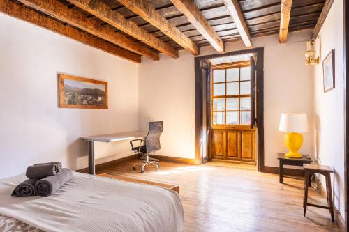 1 dormitorio con cama, escritorio y ventana en Casa Argelia, en Vilaflor