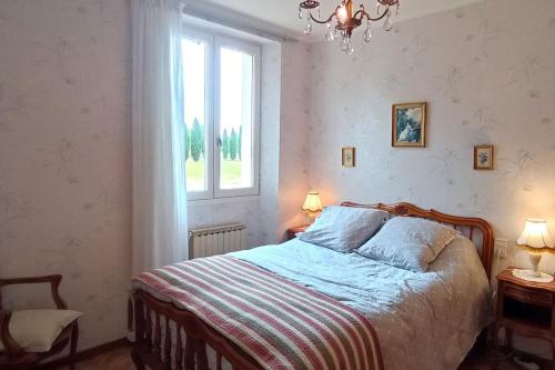 a bedroom with a bed and a window and a chandelier at Maison au bord du lac in Cagnac-les-Mines