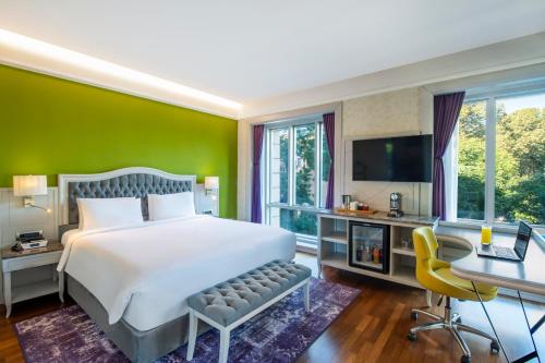 1 dormitorio con cama blanca y pared verde en Mercure Tbilisi Old Town, en Tiflis