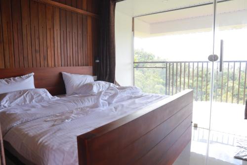 a large bed in a bedroom with a large window at Munnar ethan's valley in Anachal