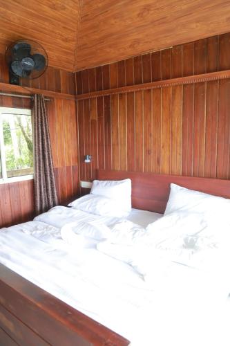 a bedroom with two beds in a wood paneled room at Munnar ethan's valley in Anachal