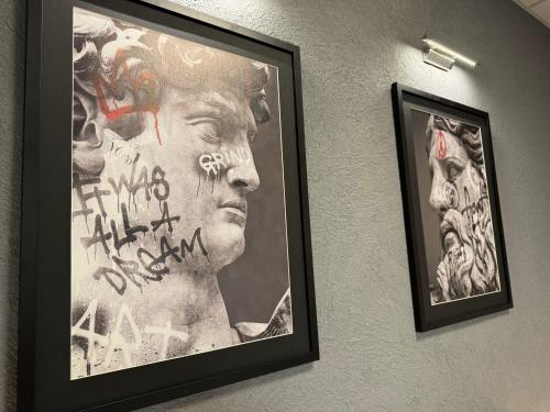 two framed pictures of a man on a wall with graffiti at Svatého Pasáž BOUTIQUE Apartments with free parking in Trnava