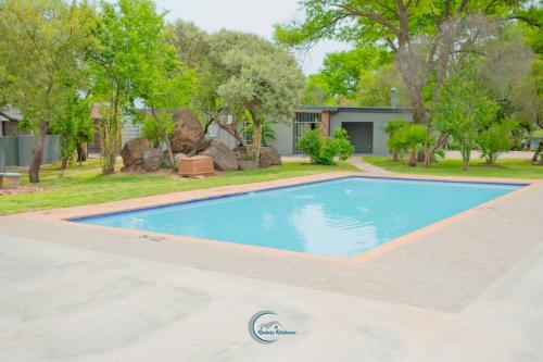 una piscina frente a una casa con árboles en Rinkase residence, en Pretoria