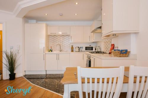 a kitchen with white cabinets and a table and chairs at The Flat 2 by Sheryl - Stone throw to Northampton Gen Hosp & Town Centre in Northampton