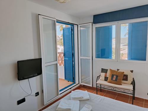 a room with a bed and a tv and some windows at Pita 2 in La Isleta del Moro