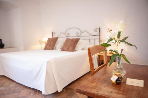 una camera da letto con un letto e un tavolo con un vaso di fiori di Monasterio de San Francisco a Palma del Río