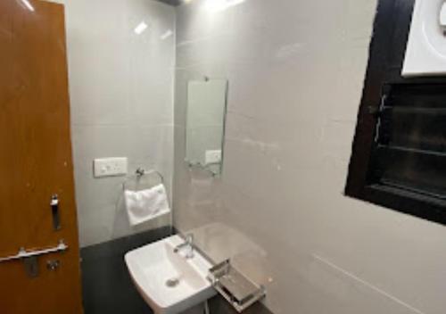a white bathroom with a sink and a mirror at Erisha Tadoba Chandrapur in Mohurli