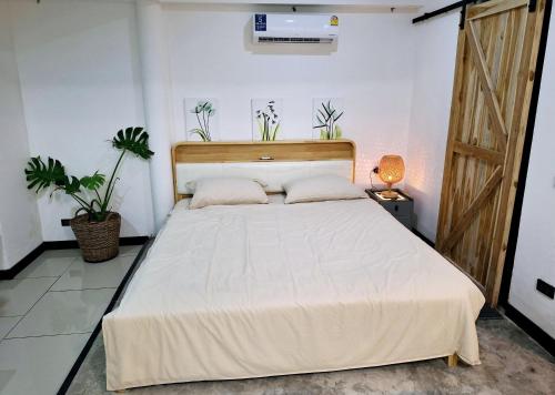 Bali-style studio apartment في Ban Madua Wan: غرفة نوم بسرير كبير في غرفة بها نباتات