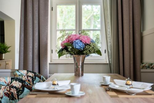 a vase of flowers on a table in front of a window at SCHLOSSRESIDENZ - Boutique Apartments & Hotel Suiten in Schloß Ricklingen