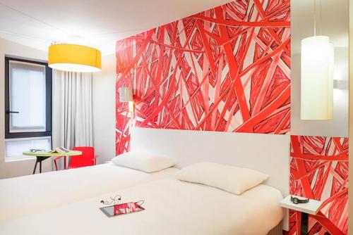 um quarto com uma cama branca e uma parede vermelha em ibis Styles Paris La Défense Courbevoie em Courbevoie