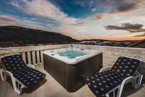 a hot tub on a balcony with two chairs at Apartments Villa Monique in Rogoznica