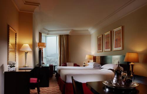 メッカにあるプルマン ザムザム マッカのベッド2台、テーブルと椅子が備わるホテルルームです。