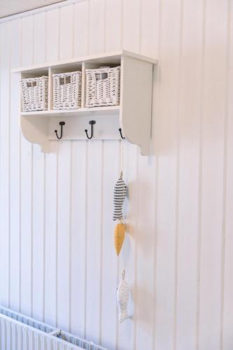 a white wall with a shelf with wicker baskets at Drømmehus Ferienwohnungen in Nørre Nebel