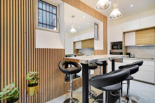 une cuisine avec une table et des tabourets noirs dans l'établissement Cosy apartment - 2BR-6P - Haut Marais, à Paris