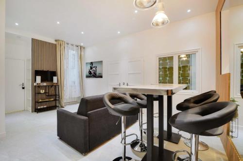 ein Wohnzimmer mit einem Tisch und schwarzen Stühlen in der Unterkunft Magnifique 3 pièces au cœur du haut Marais in Paris