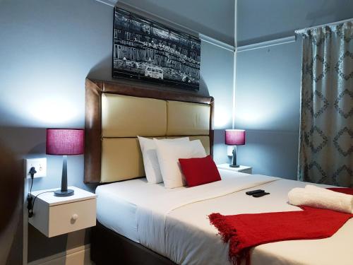 1 dormitorio con 1 cama blanca grande con almohadas rojas en Kingsworth inn Port Elizabeth en Puerto Elizabeth