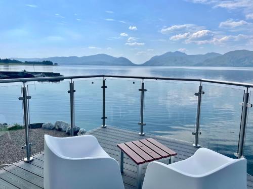 a deck with two white chairs and a table and water at Beach Houses with Hot Tubs in Glencoe
