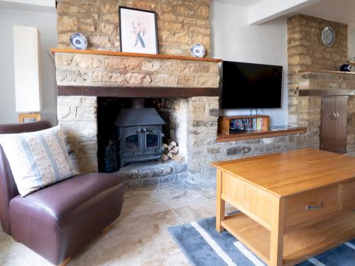 a living room with a stone fireplace with a television at Quarry Cottage Courtyard Garden Pass the Keys in Cirencester