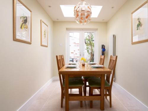 a dining room table with chairs and a chandelier at Quarry Cottage Courtyard Garden Pass the Keys in Cirencester