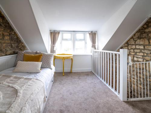 a attic bedroom with a bed and a window at Quarry Cottage Courtyard Garden Pass the Keys in Cirencester