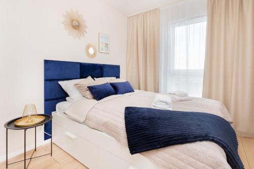 Apartment Sucha Nowa Letnica by Renters في غدانسك: غرفة نوم بيضاء و زرقاء مع سرير كبير